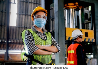 Fabrikarbeiterin oder Technikerin mit Hygienemaske stehen mit ihrem Mitarbeiter als Hintergrund mit voller Selbstverständlichkeit da.