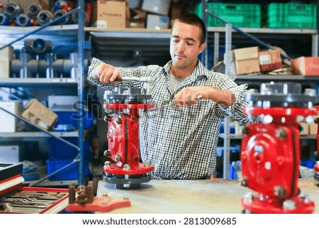 Factory worker assembles shutoff valves using various tools