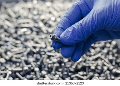 Factory Worker In Blue Plastic Gloves Showing Steel Bolt