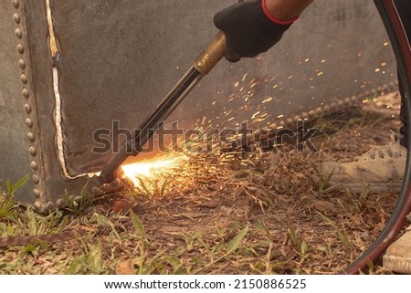 A factory worker cuts metal using an acetylene torch. Manual plasma cutting in a steel plant is full of sparks. gas fire blowing hot iron
