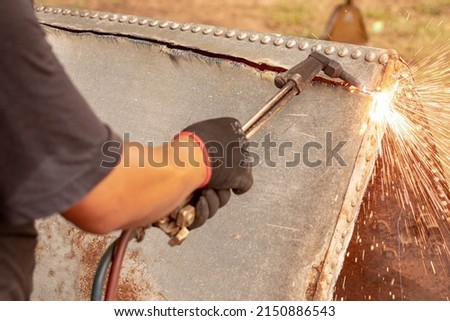 A factory worker cuts metal using an acetylene torch. Manual plasma cutting in a steel plant is full of sparks. gas fire blowing hot iron