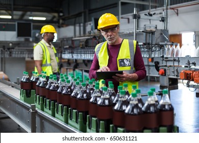 Factory worker with digital tablet monitoring drinks production line at factory - Powered by Shutterstock