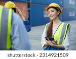 factory worker or engineer holding tablet and talking with coworker in containers warehouse storage