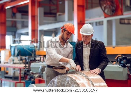 Factory worker foreman and engineer manager working together at industrial worksite , wearing hard hat for safety