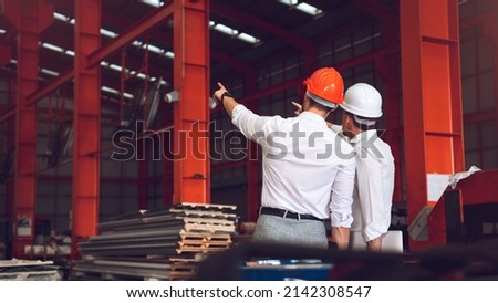 Factory worker foreman and engineer manager working together at industrial worksite , wearing hard hat for safety