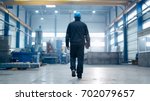 Factory worker in a hard hat is walking through industrial facilities.
