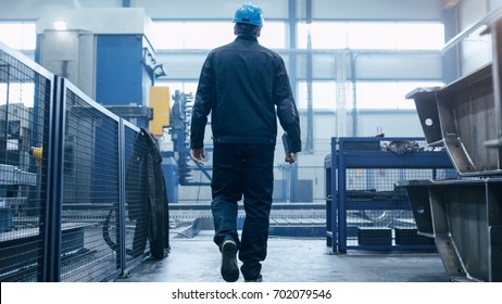 Factory Worker In A Hard Hat Is Walking Through Industrial Facilities.