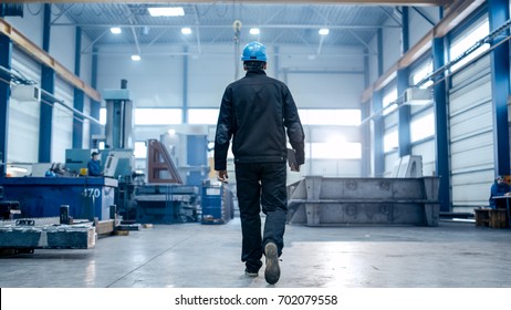 Factory worker in a hard hat is walking through industrial facilities.