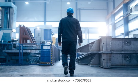 Factory Worker In A Hard Hat Is Walking Through Industrial Facilities.