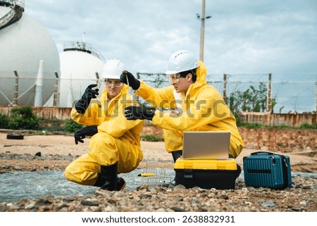 Factory worker in hazmat suit performs environmental inspection and collects oil and water samples from petroleum beach to detect marine contamination and toxic spill.