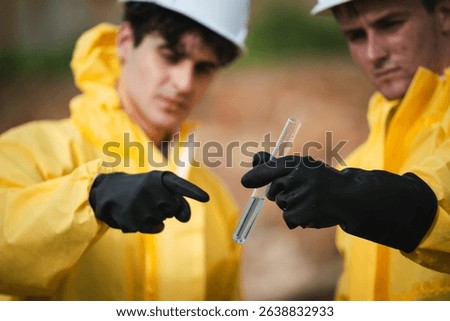 Factory worker in hazmat suit performs environmental inspection and collects oil and water samples from petroleum beach to detect marine contamination and toxic spill.