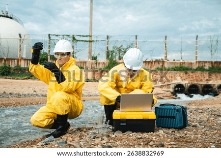 Factory worker in hazmat suit performs environmental inspection and collects oil and water samples from petroleum beach to detect marine contamination and toxic spill.