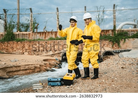 Factory worker in hazmat suit performs environmental inspection and collects oil and water samples from petroleum beach to detect marine contamination and toxic spill.