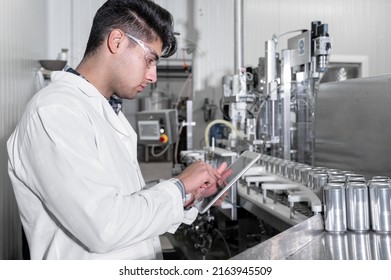 Factory Worker Inspecting Production Line On Beverage Factory With Computer Tablet. High Quality Photo