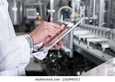 Factory Worker Inspecting Production Line On Beverage Factory With Computer Tablet. High Quality Photo