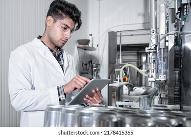 Factory Worker Inspecting Production Line On Beverage Factory With Computer Tablet. High Quality Photo