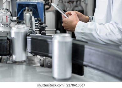 Factory Worker Inspecting Production Line On Beverage Factory With Computer Tablet. High Quality Photo