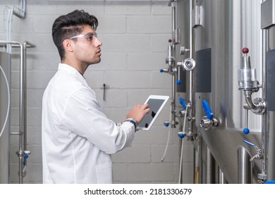 Factory Worker Inspecting Production Line On Beverage Factory With Computer Tablet. High Quality Photo