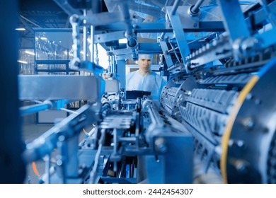 Factory worker inspecting production line automatic machine for manufacture of sterile medical bandage and masks made of non woven material. - Powered by Shutterstock