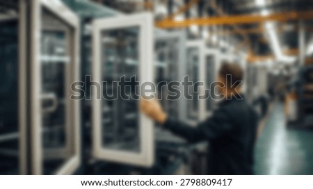 A factory worker inspects window frames in a modern manufacturing facility. The image captures the process of quality control and the industrial environment.
