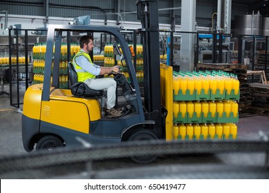 Factory worker loading packed juice bottles on forklift in factory - Powered by Shutterstock