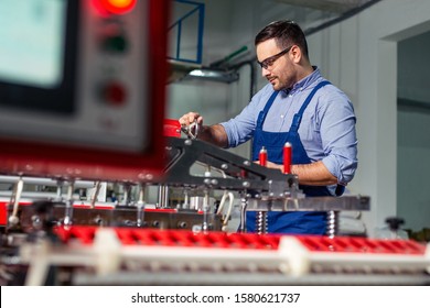 Factory Worker Maintaining Plastic Bag Machine In The Industry.