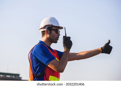 Factory worker man in hardhat talks on two-way radio with giving thumbs up, Foreman control loading containers box from cargo