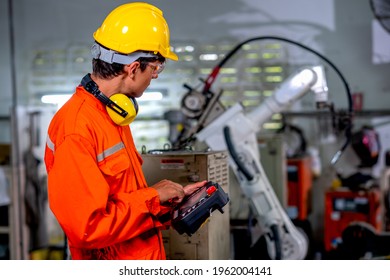 Factory Worker Man Hold Controller To Control Metal Welding Robotic Machine And Work In Workplace Area. Industrial And Technology Support System Help In Working Of Employee Concept.