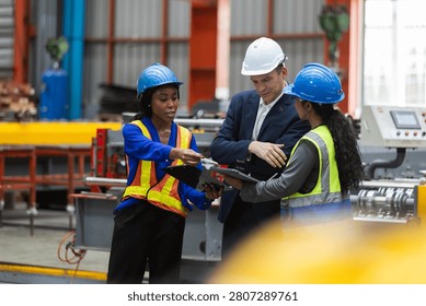factory worker, manager, and engineer reviewing manufacturing industry safety protocols on tablet while wearing hardhat and vest, showing professional engaged teamwork during discussion.