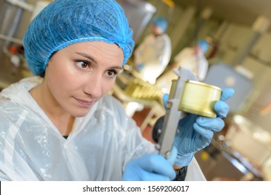 Factory worker measuring can with calipers