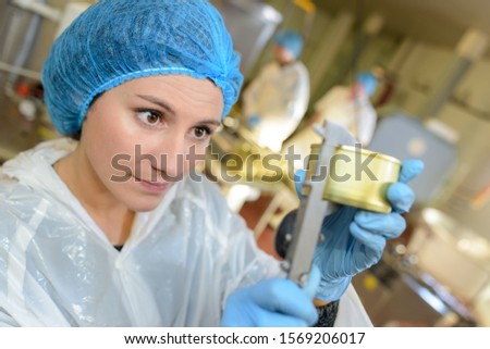 Factory worker measuring can with calipers