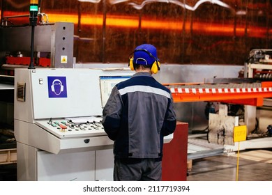 Factory worker operating CNC machine in metalworking workshop.