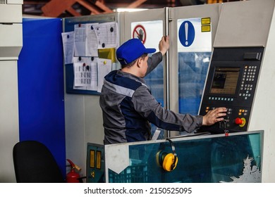 Factory worker operating CNC machine in metalworking workshop.