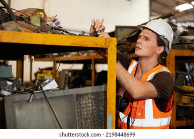 Factory Worker Picking Scrap Metal On Shelf In Old Warehouse