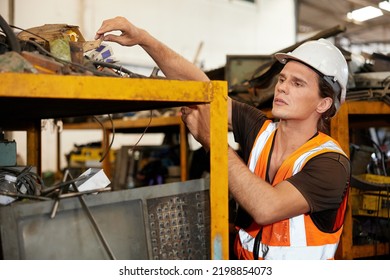 Factory Worker Picking Scrap Metal On Shelf In Old Warehouse