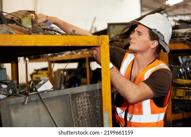 Factory Worker Picking Scrap Metal On Shelf In Old Warehouse