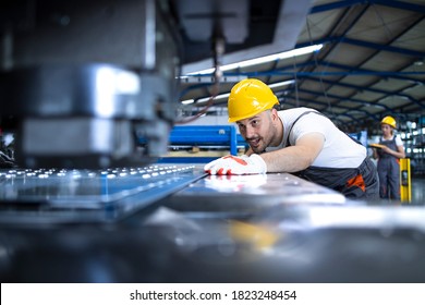 Factory worker in protective uniform and hardhat operating industrial machine at production line. People working in industry. - Powered by Shutterstock