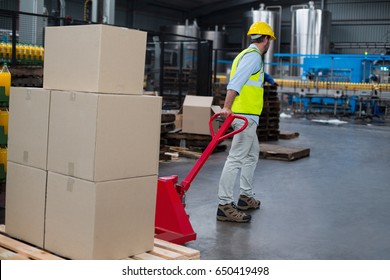 Factory worker pulling trolley of cardboard boxes in factory - Powered by Shutterstock