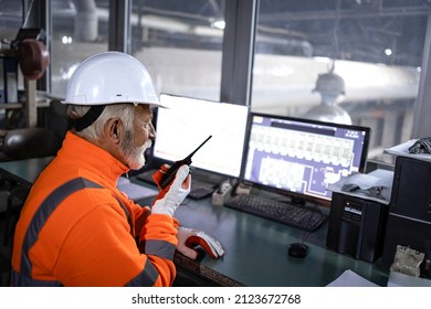 Factory worker in safety equipment monitoring industrial machines and production remotely in control room. - Shutterstock ID 2123672768