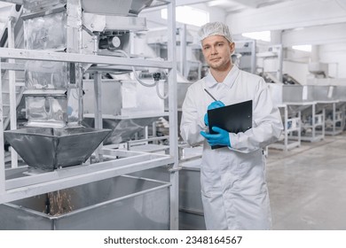 Factory worker with tablet inspecting mill for production of white flour from wheat plant. Concept food industry banner.