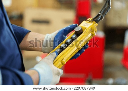 Factory worker - technician controlling a heavy crane in factory close up at his hands holing a crane controller.