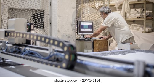 Factory Worker Technician Works On Large CNC Digital Cutter Machine For Cutting Fabric Textile Material