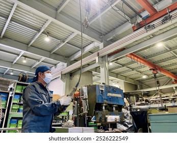 A factory worker uses a remote controller to operate a crane in japan - Powered by Shutterstock