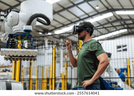 Factory worker using virtual reality headset controlling robotic arm, exploring the future of industrial automation and smart manufacturing