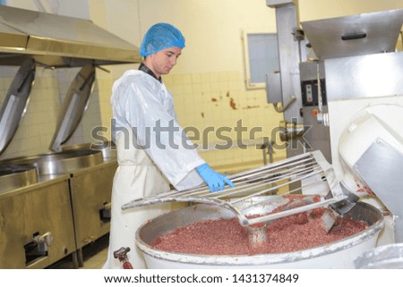 Factory worker watching over vat of food