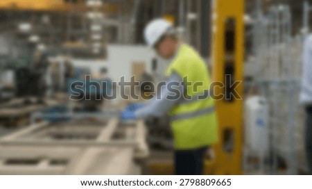 A factory worker wearing a hard hat and safety vest inspects equipment in a manufacturing facility. The image emphasizes workplace safety and industrial processes.