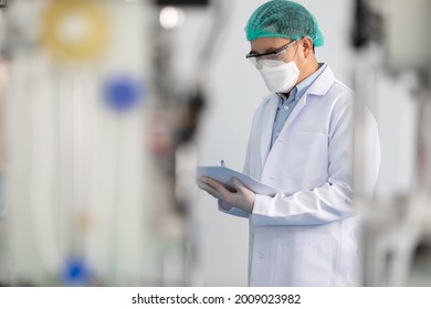 Factory Worker Wearing Medical Face Mask And Checking Production Line For Quality Control From Machine