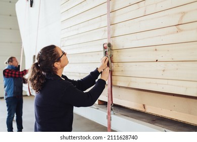 Factory worker in a woodworking workshop tightening a ratchet strap on prefabricated walls tying them in the vertical position