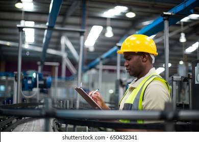 Factory worker writing on the clipboard in factory - Powered by Shutterstock