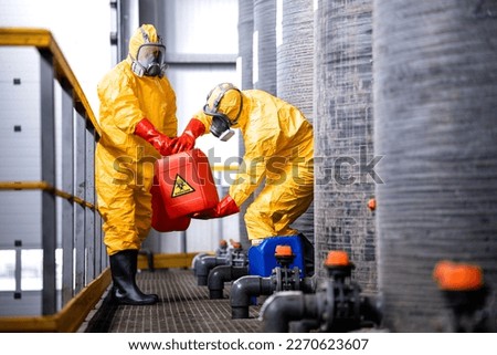 Factory workers carefully handling toxic and dangerous biohazardous waste in chemicals factory.